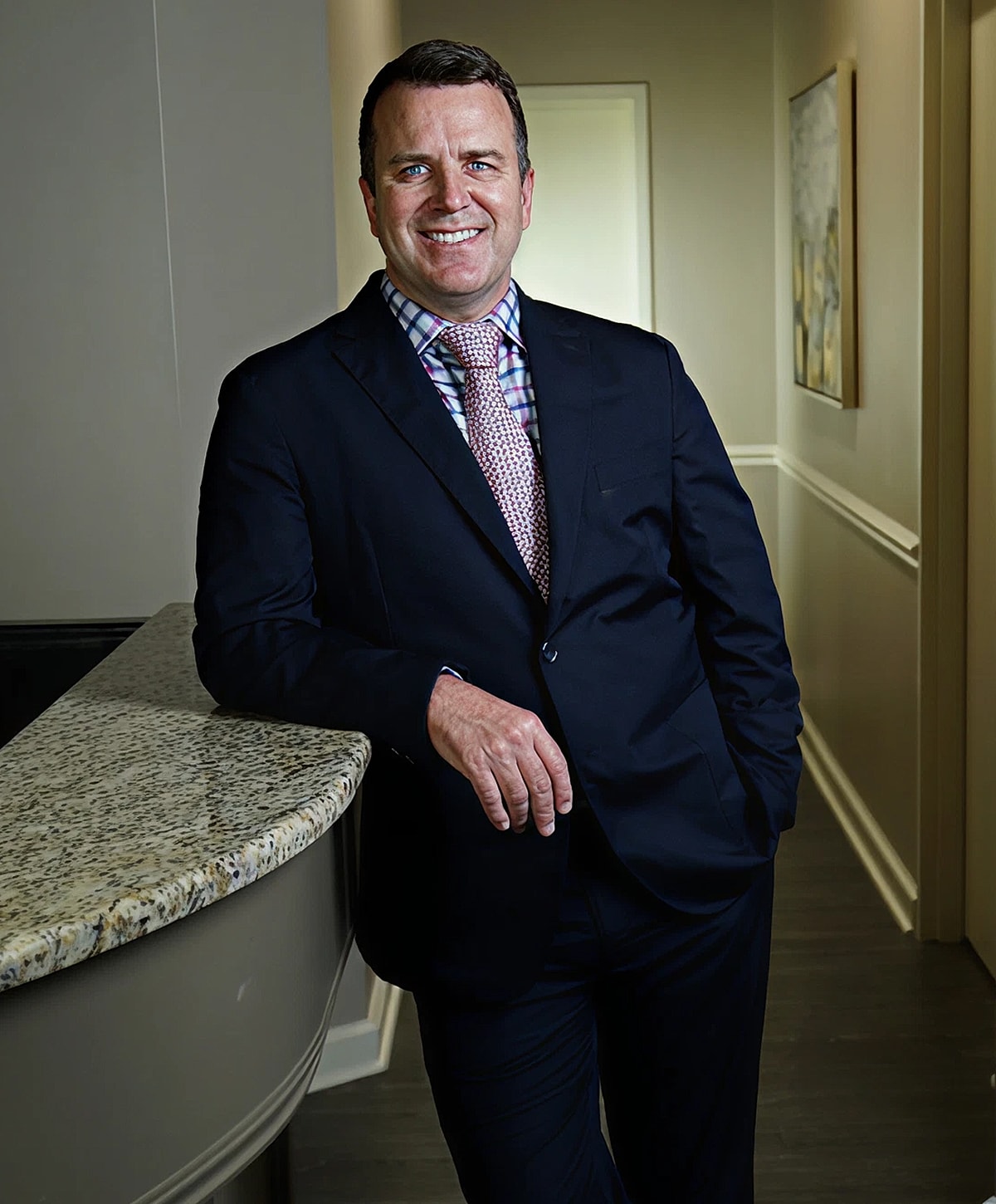 Fayetteville Motiva Implants surgeon, Dr. Spann in suit leaning against a counter