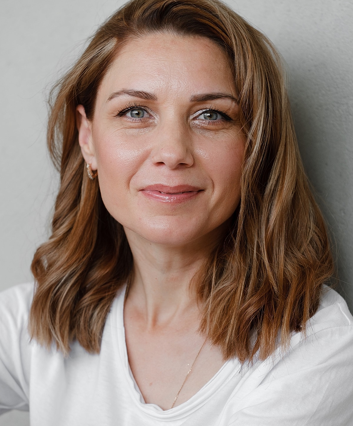 Fayetteville Blepharoplasty model with shoulder-length hair smiling at camera.